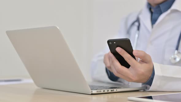 Hands of Doctor Typing on Smartphone with Laptop 