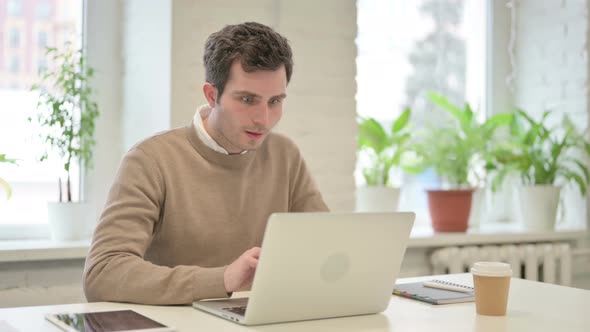 Man Celebrating Success While Using Laptop in Office