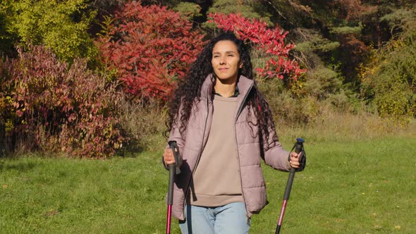 Young Attractive Carefree Woman Hiker Travels with Backpack Trekking Sticks Walking Outdoors in