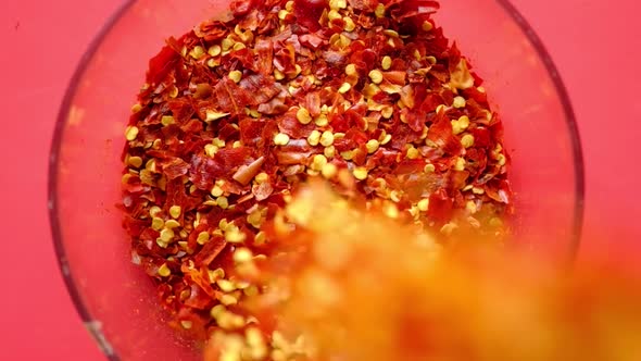 Red Chili Pepper Flakes Dropping in a Bowl on Red Background