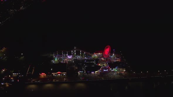 AERIAL: Breathtaking View on Santa Monica Pier at Night with Ferris Wheel and Colorful Lights, 