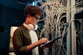 Serious young IT man working in data center standing at open server rack cabinet - PhotoDune Item for Sale