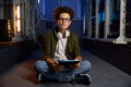 Teenager IT worker sitting on floor of modern server room working on tablet - PhotoDune Item for Sale