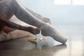 Ballerina sitting on floor putting on pointe shoes before choreography lesson - PhotoDune Item for Sale