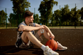 Young adult basketball player rest on urban street court - PhotoDune Item for Sale