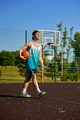 Happy satisfied teenager sportsman walking with ball on street basketball court - PhotoDune Item for Sale