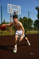 Active teenager basketball player practicing with ball on street court - PhotoDune Item for Sale
