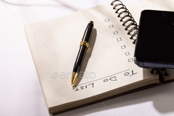 Image of notebook with to do list and copy space, pen and smartphone on white surface