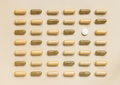 Mix of medical capsules with onewhite pill in lines on light beige top view. Dietary supplements - PhotoDune Item for Sale