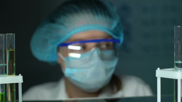 Illegal Lab Worker Looking at Camera, Toxic Liquids in Test Tube Rack, Business