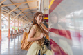 Beautiful asian traveler with backpack getting on a train at a platform of railway station - PhotoDune Item for Sale