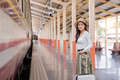 Asian women waiting for train station and carrying a suitcase planning happy holiday vacation - PhotoDune Item for Sale