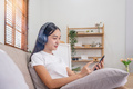 Young Asians woman listen to music on couch in living room at home. Happy Asia female using mobile - PhotoDune Item for Sale