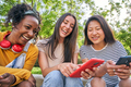 Three happy women using cell phone outdoors. Classmates having fun watching something on the mobile. - PhotoDune Item for Sale