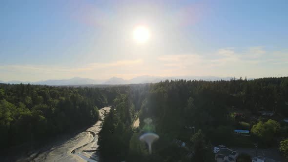 Small bridge dam, distant mountains, green trees small low tide river creek flying toward the sunset
