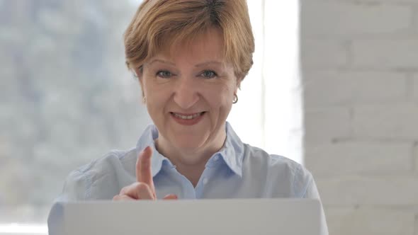 Old Woman Pointing at Camera at Work