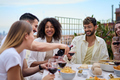 Young smiling Caucasian man serving red wine to guests at food table in celebration happy friends. - PhotoDune Item for Sale