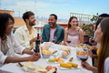 Laughing group of multiracial young friends enjoying lunch together outdoors. Cheerful people party. - PhotoDune Item for Sale