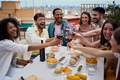 Gathering cheerful young multiracial friends toasting red wine and celebrating party on rooftop.  - PhotoDune Item for Sale