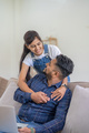 Young indian couple using laptop while sitting on couch and floor. Happy smiling indian woman - PhotoDune Item for Sale
