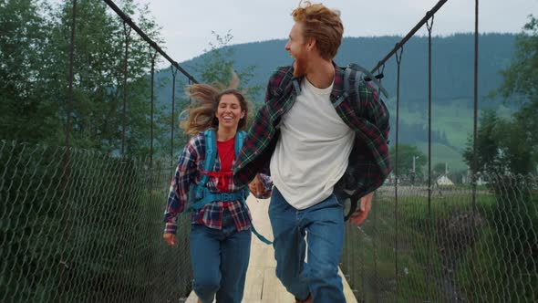 Emotional Couple Travelers Running on Mountains Bridge