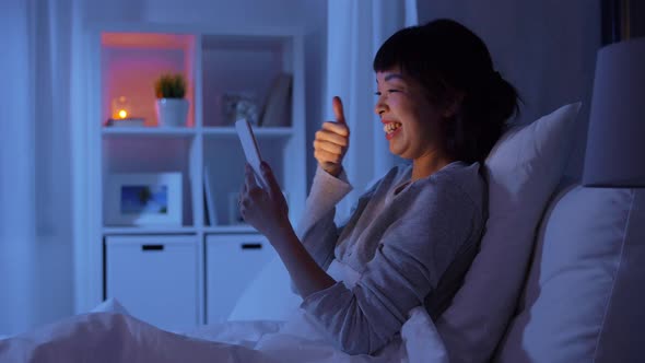 Woman with Phone in Bed Having Video Call at Night