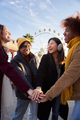 Vertical group smiling multi-ethnic people joining hands at amusement park sunny winter vacations. - PhotoDune Item for Sale