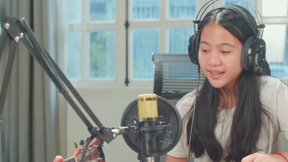 Asian Kid Girl Singing Into Microphone While Boy Playing The Guitar During Online Livestream