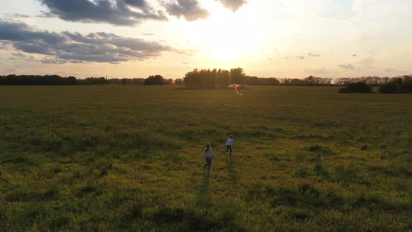 The Mother and Boy Run with a Kite on a Green Field