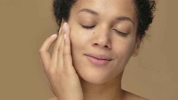 Beauty Portrait of Young African American Woman Applying Skincare Cream on Face