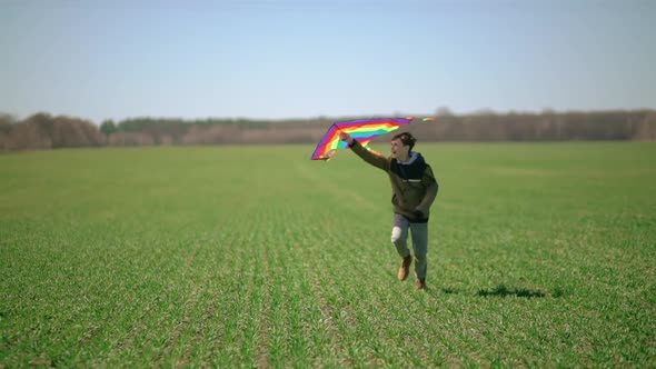 A Boy Runs Across a Green Field with a Kite