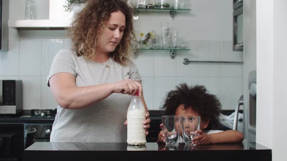 White Mother and Her Mixed Black Daughter at the Kitchen  Woman Pouring Milk in the Glass