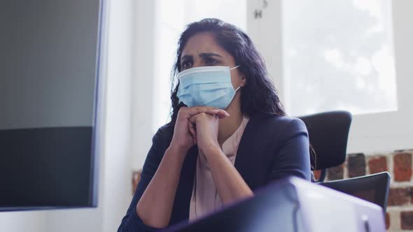 Woman wearing face mask sitting on her desk at office