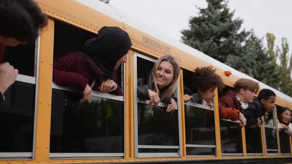 Joyful Teens with Heads Out of School Bus Windows