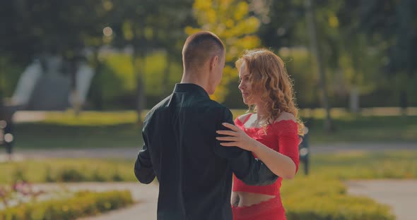 Elegant Man Takes a Partner By the Waist and Begins to Dance on a City Street