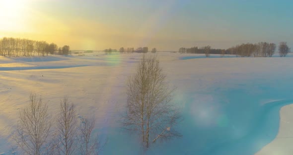 Aerial View of Cold Arctic Field Landscape Trees with Frost Snow Ice River and Sun Rays Over Horizon