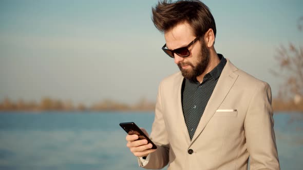 Freelancer Man Mobile Working Outdoors Walking And Using Cellphone. Businessman In Suit.