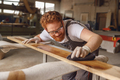 Craftsman coating a wooden board with protective oil in a workshop. Process of making a - PhotoDune Item for Sale