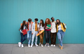 Large group of cheerful young people leaning against blue wall. Multicultural college students. - PhotoDune Item for Sale