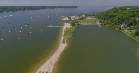 Flying Away from a Thin Strip of Land and Boats Anchored on Harbor