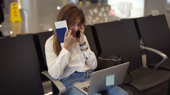 Stylishpretty Girl in White Shirt Uses Phone and Laptop to Work at Airport While Waiting Boarding at