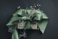 Paper gift box with olive green ribbon tied in a bow, small flowers, black background. - PhotoDune Item for Sale