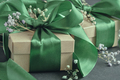 Paper gift boxes with green ribbons tied in a bow, small flowers, black background. - PhotoDune Item for Sale