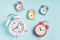 Five alarm clocks of different colors show different times. Start of the day,  different time zones. - PhotoDune Item for Sale