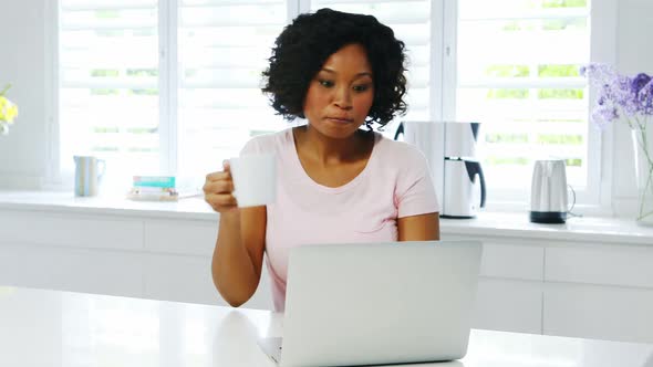 Woman using laptop in kitchen