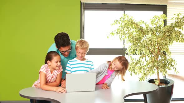 Teacher and kids using laptop in classroom