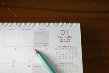 Calendar page with a pencil on a wooden table with the date: January 1, 2023.