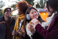 Happy smiling multiracial friends eating chocolate with churros together outdoors. Winter festival. - PhotoDune Item for Sale