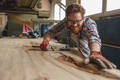 Close up of smiling craftsman working with chisel while cutting wooden plank in carpentry workshop - PhotoDune Item for Sale