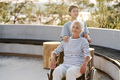 Senior woman in wheelchair walking with nurse outdoors - PhotoDune Item for Sale
